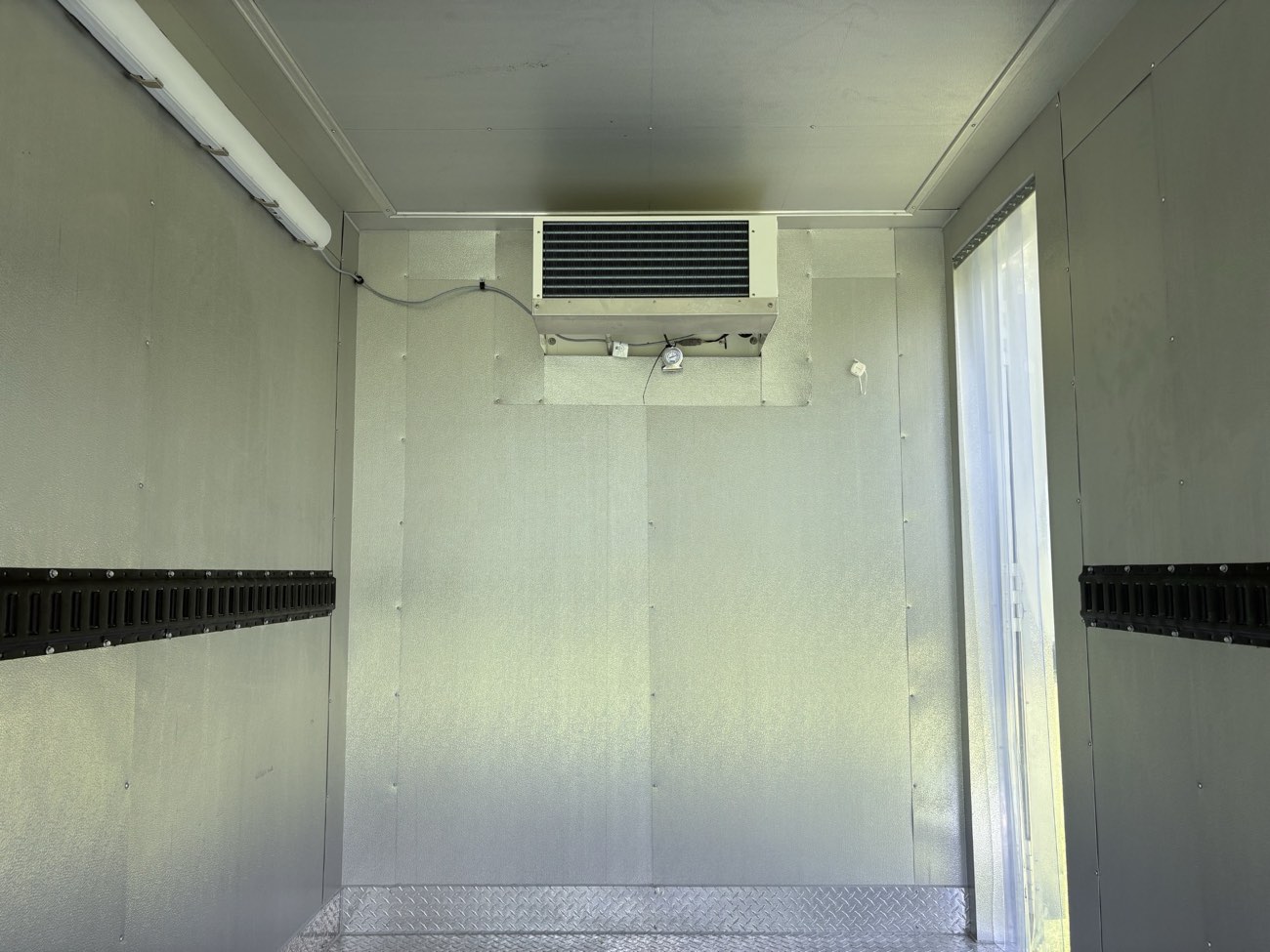 Interior of a Keep It Cool refrigerated trailer showing the refrigeration unit with thermometer, interior light, and diamond plate floor